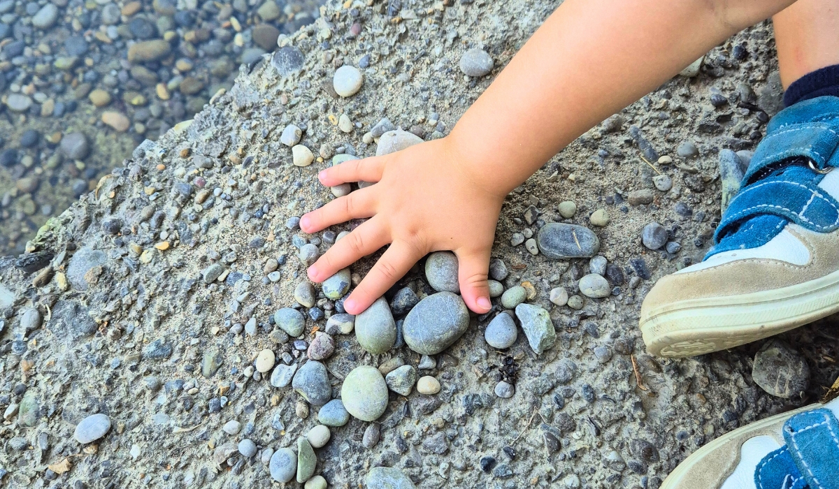 Kinderhand mit Steinen am Boden