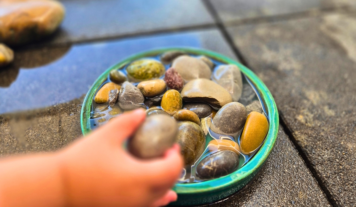 Steine in einem Untersetzer, eine Kinderhand mit einem Stein
